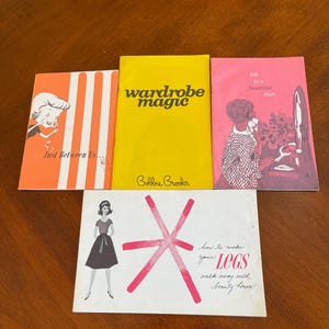May include: A collection of vintage fashion booklets. The booklets have titles like "Wardrobe Magic" and "Just Between Us." The covers feature illustrations and text in various colors, including orange, yellow, and pink. One booklet has the text "how to make your LEGS walk away with beauty honors!"