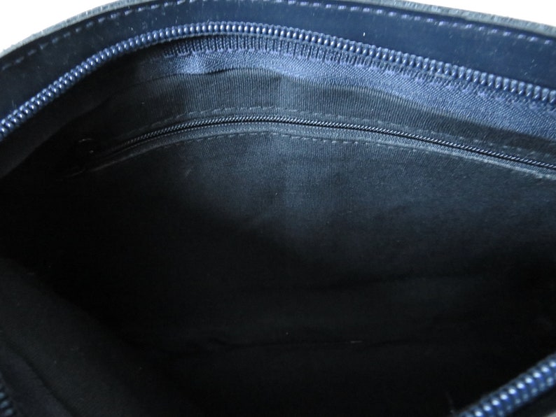 May include: The inside of a dark blue leather bag with a zipper closure. The lining is a dark fabric.