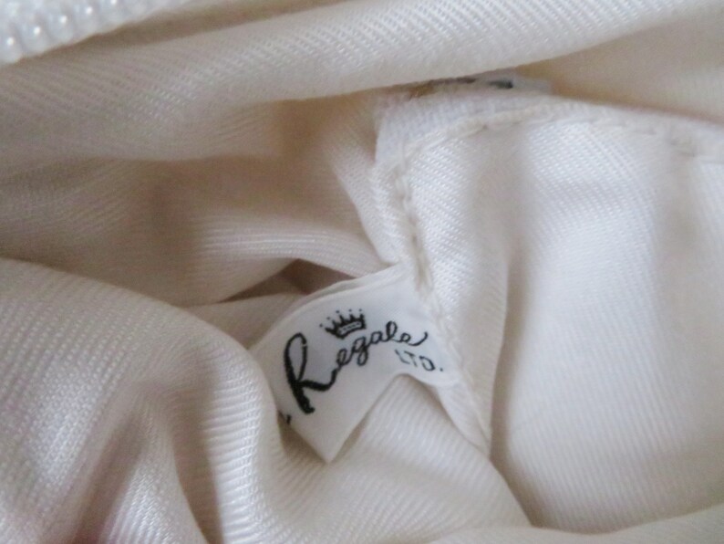 May include: White fabric with a white label that says "Regale Ltd." with a crown above the word "Regale".