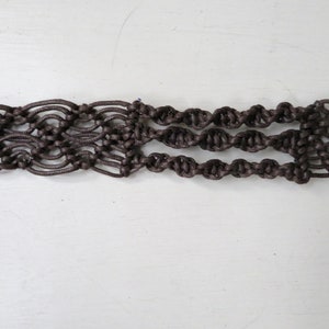 Puede incluir: Un cintur&oacute;n de macram&eacute; marr&oacute;n con un dise&ntilde;o tejido. El cintur&oacute;n presenta una serie de patrones anudados, creando un accesorio texturizado y decorativo. El cintur&oacute;n mide aproximadamente 5 cm de ancho.