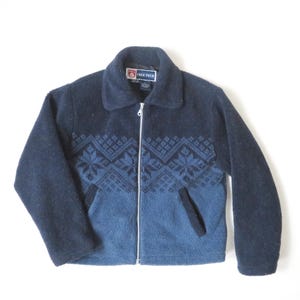 May include: A blue fleece jacket with a zipper closure and a patterned design on the front. The jacket has a stand-up collar and a Free Tech label.