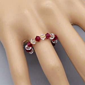 Op de afbeelding: Een ring van rode en heldere kristallen kralen op een hand van een mannequin.