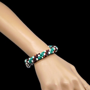 Pode incluir: Um bracelete de contas multicolorido com contas turquesa, brancas e marrons. O bracelete é feito com contas pequenas e redondas e tem um fecho prateado.