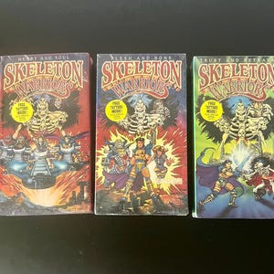 May include: Three Skeleton Warriors VHS tapes titled Heart and Soul, Flesh and Bone, and Trust and Betrayal. Each cover features colorful illustrated characters, a yellow circular sticker stating Free Tattoos Inside, and the Skeleton Warriors logo.