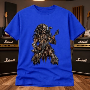May include: A royal blue short-sleeved t-shirt featuring a graphic print of a creature with dreadlocks and a helmet, wearing armour and playing a black electric guitar shaped like a V. The creature is adorned with skull-like decorative elements.