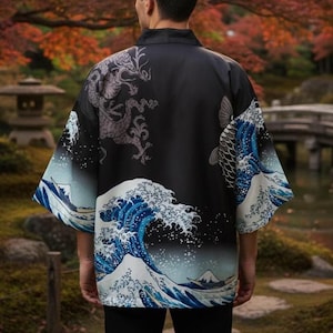 Könnte beinhalten: Schwarze Kimono-Jacke mit einem Drachen- und Koi-Fisch-Design. Die Ärmel und der untere Teil der Jacke zeigen ein blau-weißes Wellenmuster. Die Jacke wird von einer Person im Freien getragen.