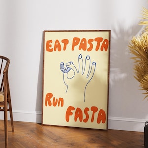 Puede incluir: Un póster enmarcado con las palabras "EAT PASTA RUN FASTA" en naranja, texto estilizado. Un dibujo lineal azul de una mano haciendo un gesto de "ok" con pasta en los dedos está en el centro. El fondo es amarillo claro.