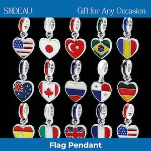Puede incluir: Colgantes plateados en forma de corazón con banderas de varios países. Los colgantes incluyen banderas de EE. UU., Japón, Turquía, Brasil y más. El texto "Gift for Any Occasion" y "Flag Pendant" son visibles. Cada uno tiene un esquema de color rojo, blanco y azul.