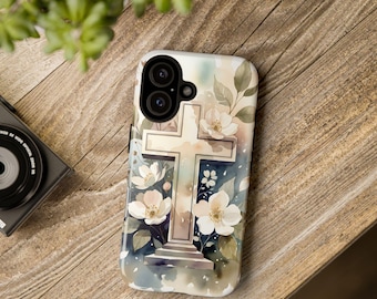 May include: A phone case featuring a watercolor design of a cross with white flowers and green leaves. The case has a light-colored background with a soft, artistic aesthetic. The phone case is on a wooden surface.