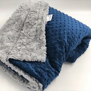 May include: A soft, blue and gray weighted blanket with a textured, dimpled side and a fluffy, plush side.