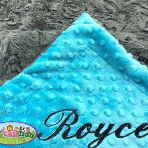 May include: A turquoise blue minky baby blanket with a gray minky backing. The blanket is personalized with the name "Royce" embroidered in black.