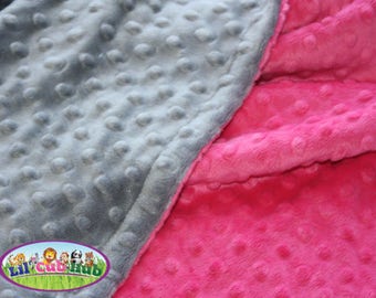 May include: A soft, gray and pink baby blanket with a textured, dotted pattern. The blanket is made of two different fabrics, one gray and one pink.