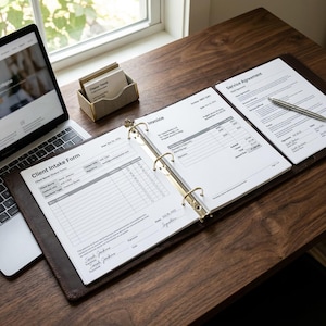 Puede incluir: Un ordenador portátil, un tarjetero y una carpeta abierta con documentos están sobre un escritorio de madera oscura. La carpeta contiene una factura y un formulario de admisión de clientes. Un bolígrafo descansa sobre un acuerdo de servicio.