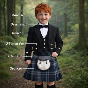 May include: A young person wearing a traditional Scottish kilt outfit. The ensemble includes a black jacket, waistcoat, bow tie, and a tartan kilt in blue and green. A sporran is also visible. The background is a blurred forest scene.