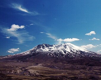 May include: A snow-capped mountain with a blue sky and white clouds in the background.