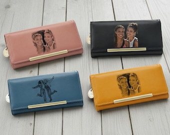 Puede incluir: Cuatro carteras de cuero en varios colores: rosa empolvado, negro, azul y amarillo mostaza. Cada cartera presenta una foto personalizada y un acento metálico dorado. Las carteras están cerradas y tienen un cierre de cremallera.