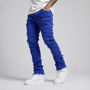 Peut inclure: Jean en denim bleu roi vif présentant un design fortement usé avec des découpes horizontales effilochées le long des jambes et un ourlet empilé et froncé aux chevilles, associé à des baskets en cuir blanc et un t-shirt blanc uni.