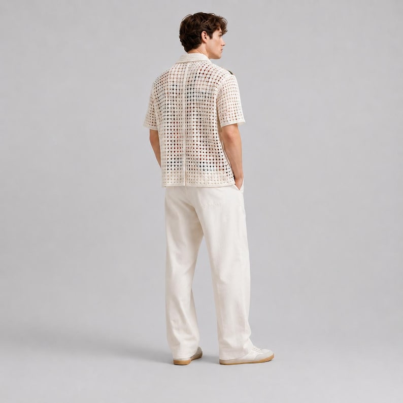 Pode incluir: Uma camisa de manga curta com bot&otilde;es em tom branco sujo, apresentando um padr&atilde;o de croch&ecirc; de malha aberta em forma de grade. &Eacute; combinada com cal&ccedil;as retas a condizer em branco sujo e t&eacute;nis claros, criando um conjunto monocrom&aacute;tico.