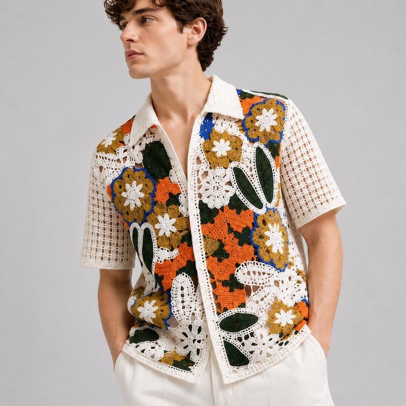 Pode incluir: Uma camisa de manga curta com bot&otilde;es e constru&ccedil;&atilde;o em croch&ecirc; com um padr&atilde;o floral multicolorido. O design incorpora fios brancos, laranja, verde-escuro e azul, com uma textura de malha aberta em forma de grade nas mangas e na gola.