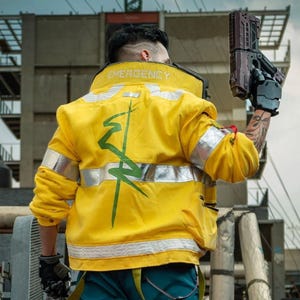 May include: A yellow jacket with silver reflective stripes and the word "EMERGENCY" on the collar. The jacket has a green graphic on the back. The person is wearing teal trousers, black gloves, and holding a futuristic gun.