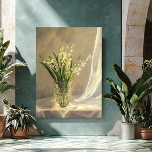 Puede incluir: Una impresión enmarcada de una naturaleza muerta con un jarrón de cristal transparente lleno de flores de lirios de los valles. El jarrón está sobre una tela blanca, con una cortina transparente al fondo. La imagen está sobre una pared turquesa, con plantas en macetas en primer plano.