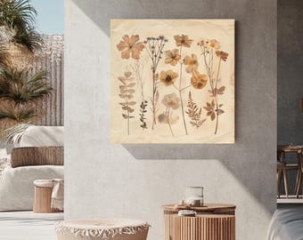 May include: A square canvas print featuring pressed flowers in shades of brown and beige. The botanical artwork showcases various dried plants and flowers, creating a natural and earthy aesthetic. The print is displayed on a neutral-colored wall.