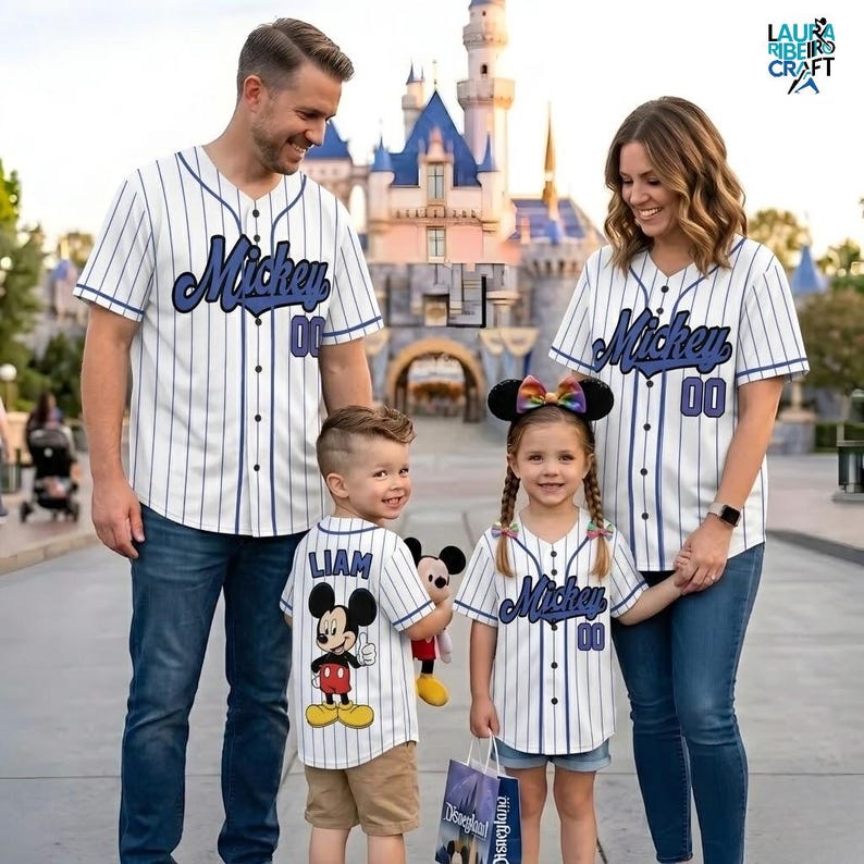 A family of four, consisting of a father, mother, and two children, are posing together in front of a Disney castle. They are all wearing Mickey-themed baseball jerseys, indicating that they are likely attending a Disney theme park.