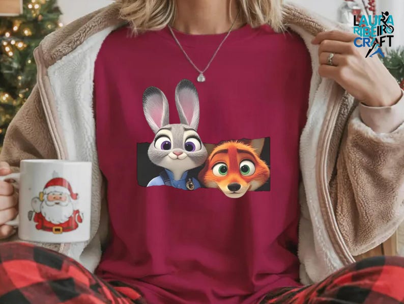 A person wearing a red shirt with a graphic of two cartoon animals, a rabbit and a fox, peeking out from behind a mug with a Santa Claus design.