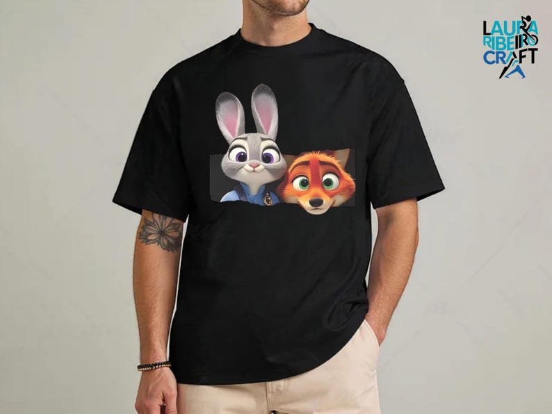 A black t-shirt with a graphic design featuring two cartoon rabbit characters, one gray and one orange, peeking out from behind a fox character.