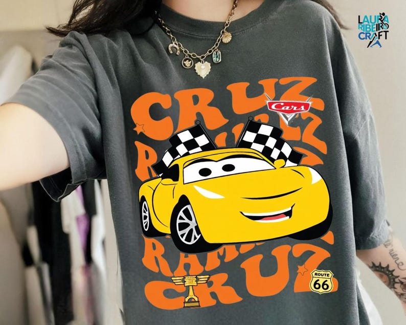 A person wearing a gray t-shirt with a graphic of a yellow race car and the text "CRUZ RUM" printed on it.