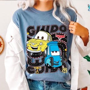 A person wearing a blue t-shirt with a graphic of two cartoon cars, one yellow and one blue, along with the text "GUIDO GUIDE" and "Cars".