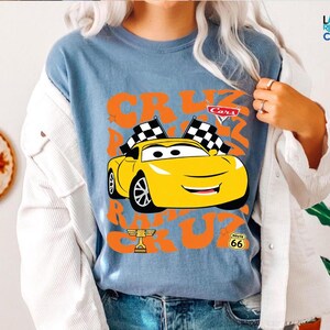 A person wearing a blue t-shirt with a graphic of a yellow car and the text "Cars" and "RACE" printed on it.