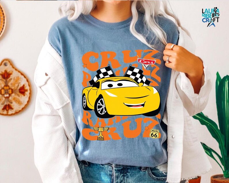 A person wearing a blue t-shirt with a graphic of a yellow car and the text "Cars" and "RACE" printed on it.