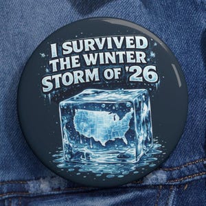 May include: A round, navy blue button with the text "I SURVIVED THE WINTER STORM OF '26" in white. The button features a graphic of a melting ice cube with the outline of the United States inside.