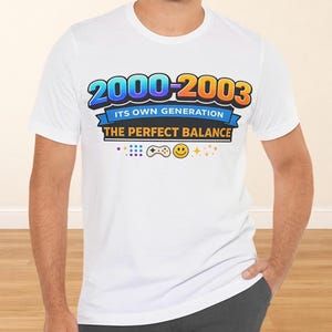 May include: White t-shirt with a colorful graphic design. The design features the text "2000-2003 ITS OWN GENERATION THE PERFECT BALANCE" in a gradient font, along with a controller and smiley face.