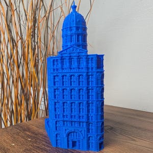 Peut inclure: Une maquette architecturale bleu vif d'un bâtiment avec un toit en dôme. Le modèle présente des fenêtres détaillées et des éléments architecturaux, mettant en valeur un design classique. Le bâtiment est d'une teinte bleue saisissante.