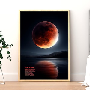 May include: A framed art print depicting a lunar eclipse over a body of water. The moon is a vibrant red-orange, reflecting in the water below. The text "lunar eclipse" is at the bottom of the print.