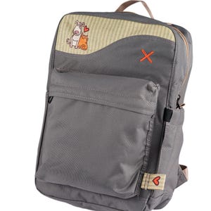 May include: A set of three ceramic mugs with a speckled, matte finish. The mugs are in shades of cream, light brown, and dark brown. Each mug has a simple, minimalist design and a rounded handle.