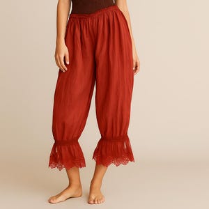 Puede incluir: Pantalones cortos de color óxido, con cintura fruncida y puños con volantes y ribete de encaje. La tela suelta y ligera cae suavemente. Los pantalones están diseñados para la comodidad y el estilo.