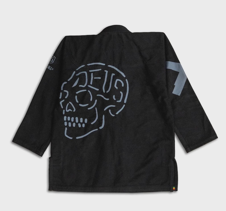 May include: Black martial arts gi with a light blue skull design on the back. The word "DEUS" is integrated into the skull design. A light blue number 7 is on the right shoulder.