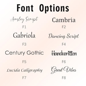 May include: A white ceramic mug with a black handle and the text "But First, Coffee" in a black, handwritten-style font. The mug is on a white surface.