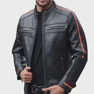 Puede incluir: Chaqueta de cuero negra con rayas naranjas en las mangas y los hombros. La chaqueta tiene cremallera frontal, múltiples bolsillos con cremallera y cuello alzado. Estilo motero clásico.