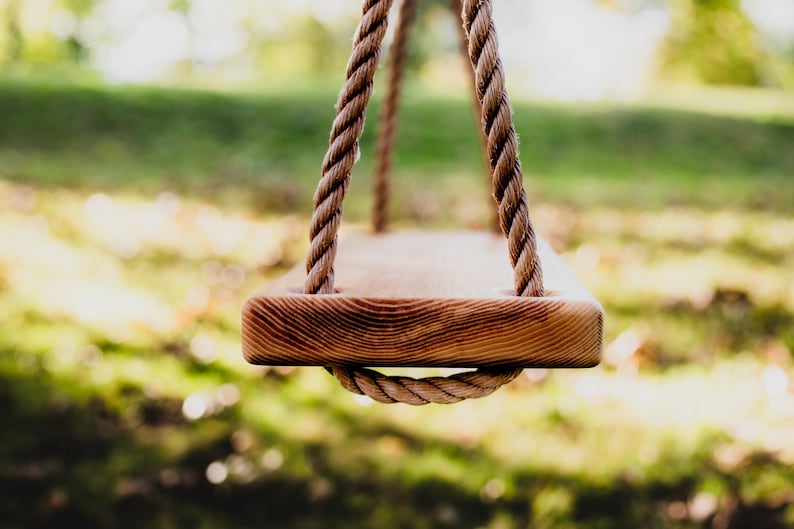 Puede incluir: Un asiento de columpio de madera con una cuerda gruesa que cuelga de una rama de &aacute;rbol. El asiento del columpio est&aacute; hecho de madera natural y tiene un aspecto r&uacute;stico.