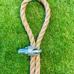 May include: A close-up of a brown rope with a metal loop and a metal clasp. The rope is on a green grassy surface.