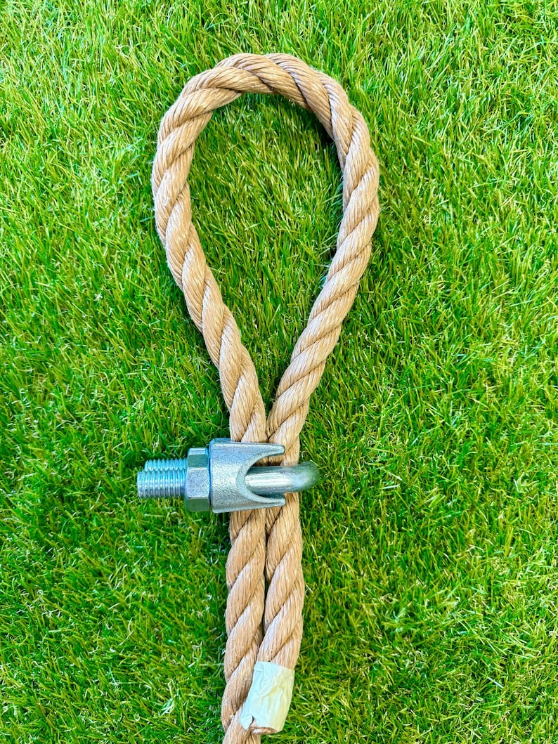 May include: A close-up of a brown rope with a metal loop and a metal clasp. The rope is on a green grassy surface.