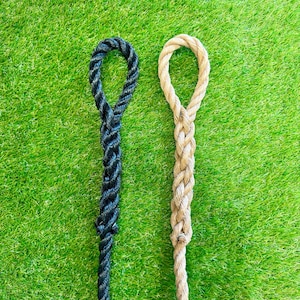 May include: Two ropes with loops at the top, one black and one beige, against a green background.