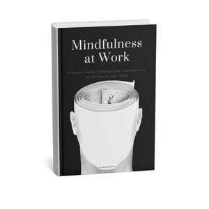 Pode incluir: Um livro de capa dura intitulado "Mindfulness at Work" com uma capa preta. A capa apresenta uma ilustração branca de uma cabeça com um papel enrolado dentro. O subtítulo do livro diz: "A Practical Guide to Reducing Stress, Improving Focus, and Building Stronger Teams."