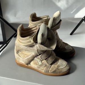 May include: A white ceramic mug with a black handle and the text "But First, Coffee" in a black, bold font. The mug is on a white surface.