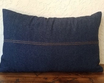 May include: A dark blue denim pillow with a brown stitched seam across the center.