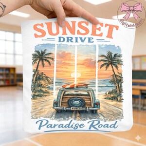 May include: White tote bag with a watercolor illustration of a vintage blue station wagon driving on a coastal road at sunset. The text "Sunset Drive" and "Paradise Road" are displayed in orange and blue.